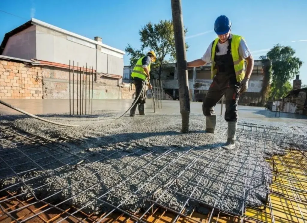 Workers pour concrete slab