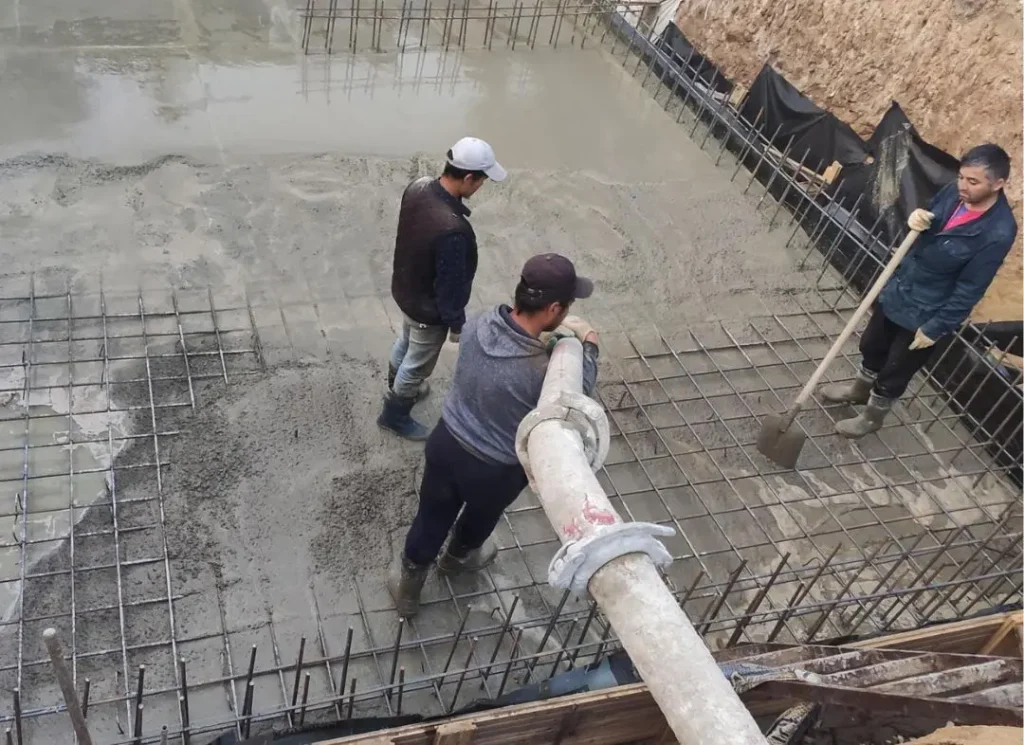Workers pouring concrete foundation