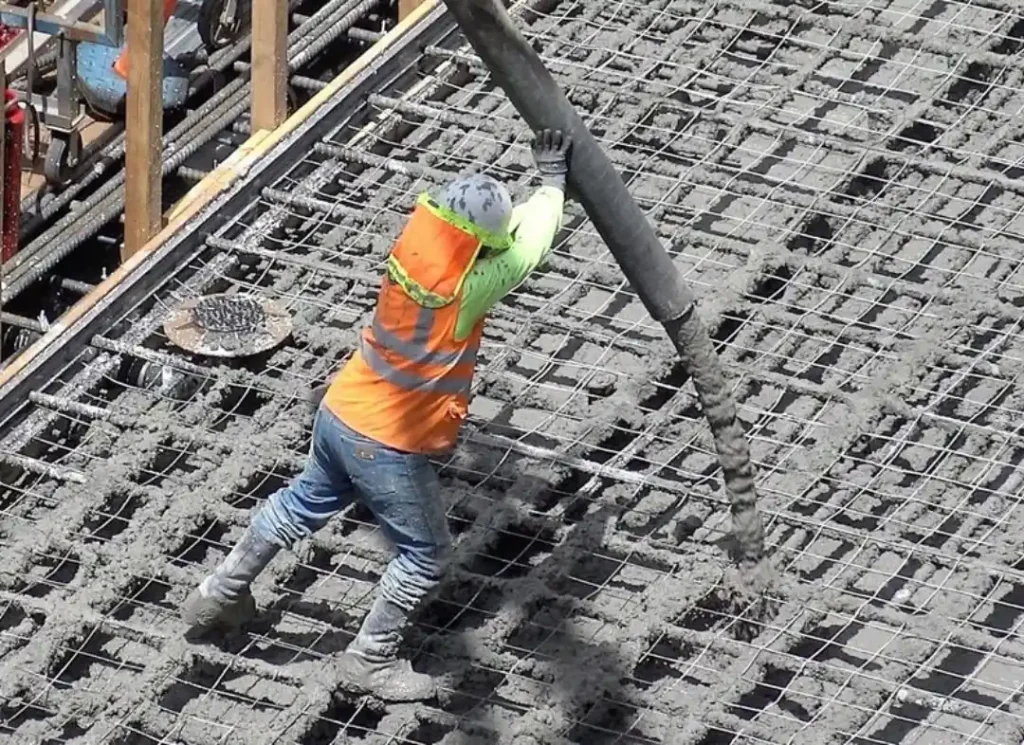 Worker pouring concrete slab.